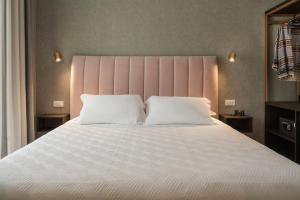 里乔内Hotel Sole的卧室配有一张白色大床和粉红色床头板
