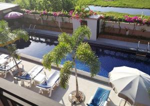 邦萨雷4 Palms Resort的棕榈树旁的游泳池边,配有椅子和遮阳伞