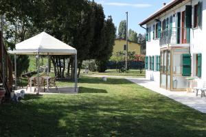 卡奥莱Casa di campagna Cà Teresa的一座花园,旁边是一座建筑,花园内配有桌子和遮阳伞