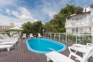 邦比尼亚斯Bombinhas Tourist Apart的一座带白色椅子的甲板上的游泳池和一座建筑