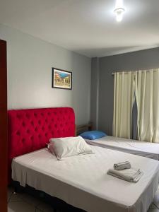 伊塔佩马Pousada Vovo Valdir的一间卧室配有两张带红色床头板的床