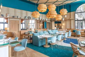 比亚里茨巴黎酒店兼咖啡馆的用餐室配有桌椅和吊灯。