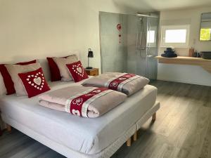 ScherwillerGite Au sauna de l’Aubach的一间卧室配有两张带红白色枕头的床