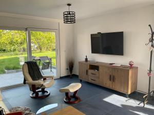 ScherwillerGite Au sauna de l’Aubach的客厅配有平面电视和椅子