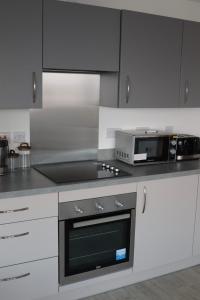 曼彻斯特Luxurious City View Apartment in Salford的厨房配有炉灶、烤箱和微波炉
