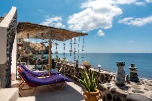 阿克罗蒂里Serenity Blue (Cave house)的一个带椅子和遮阳伞的庭院和大海