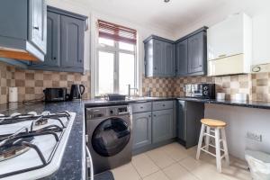 伦敦2 Bedroom Duplex Apartment的厨房配有蓝色橱柜和洗衣机。