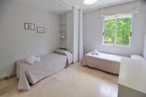 科尔多瓦Albéniz的白色的客房设有两张床和窗户。