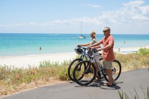巴瑟尔顿巴瑟尔顿乔格拉菲湾景度假酒店的站在海滩上自行车旁的男人和女人