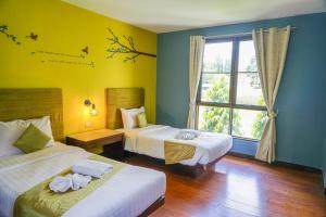 Ban Khanong Phra Taiโรงแรมวิลลา พาราดี的酒店客房设有两张床和窗户。