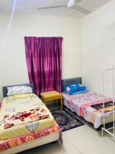 Kampong Alor GajahHomestay Zalida D Musleem的紫色窗帘间内的两张床