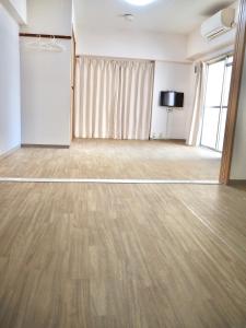 大阪UNE apartment hotel 大阪なんば的大型客房,设有木地板和平面电视。