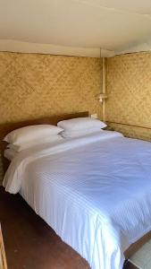 大吉岭Deoja Forest Stay的一张配有白色床单和枕头的大床
