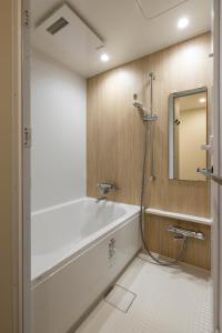 Tsuboyaアルファベットイン那覇国際通りEAST的浴室配有浴缸、淋浴和镜子