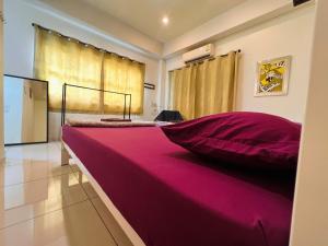 罗勇Aekkalukthai Hostel Rayong的窗户客房内的一张粉红色大床