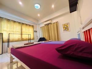 罗勇Aekkalukthai Hostel Rayong的一张大床,位于一个配有粉色毯子的房间