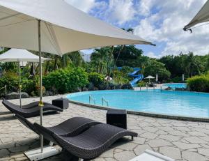 塔穆宁关岛日航酒店的游泳池旁的两把椅子和一把遮阳伞