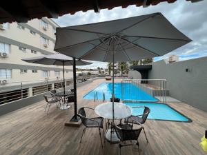 阿西斯Ônix Hotel的庭院配有桌椅和遮阳伞。
