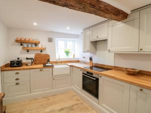 莫顿因马什Ashton House的厨房铺有木地板,配有白色橱柜。