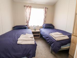 莫克姆Rosella 38的配有紫色床单和窗户的客房内的两张床
