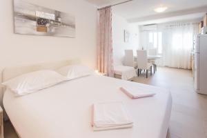 特罗吉尔Apartments Bandić - 30 meters to the beach的一间白色的卧室,配有白色的床和一间餐厅