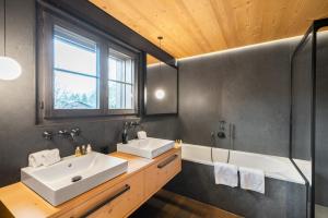 格施塔德Swiss Hotel Apartments - Gstaad的浴室配有2个盥洗盆和1个浴缸。