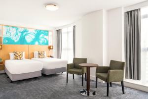 伯明翰假日伯明翰城市酒店度假村的酒店客房带两张床和一张桌子以及椅子。