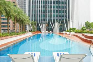 新加坡Citadines Raffles Place Singapore的一座带两把椅子的游泳池以及一座建筑