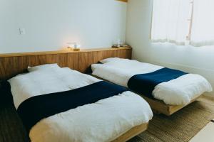 富士吉田市HOSTEL SARUYA 的两张睡床彼此相邻,位于一个房间里