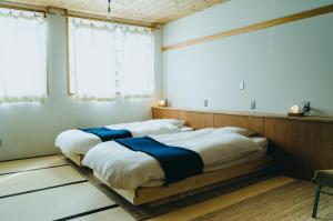 富士吉田市HOSTEL SARUYA 的配有2张床的白色墙壁和窗户客房