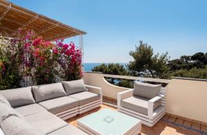 卡普里Oliveto Capri apartments的天井配有沙发和两把椅子及鲜花