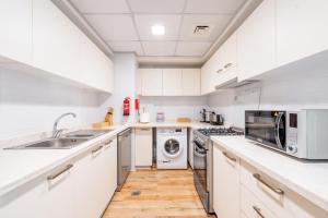 拉斯阿尔卡麦Luxury 1BR Beachfront Apartment Marjan Island的厨房配有白色橱柜、水槽和洗碗机。
