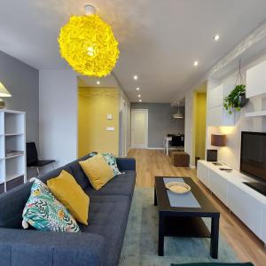 巴利亚多利德Ático Ángela的客厅配有蓝色的沙发和黄色的吊灯