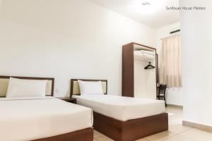 马六甲De Harmony Stay的配有白色墙壁的酒店客房内的两张床