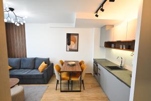 兹拉蒂博尔Tasa Apartmani的厨房以及带桌子和沙发的客厅。