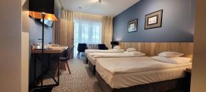 奥古斯图Hotel Wojciech的酒店客房设有三张床和一张书桌
