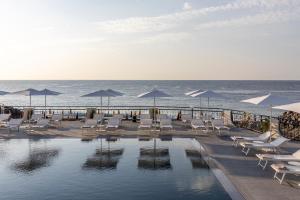 贾迪尼-纳克索斯Delta Hotels by Marriott Giardini Naxos的毗邻大海的带椅子和遮阳伞的游泳池