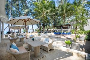 卡马拉海滩InterContinental Phuket Resort, an IHG Hotel的一个带桌椅的庭院,棕榈树