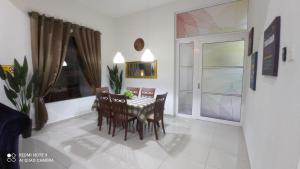 马六甲D'ZAHRA HOME - with 30ft private pool的一间带桌椅和窗户的用餐室