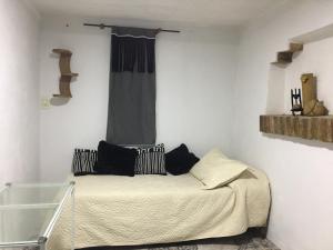 卢汉德库约Habitación doble的一间卧室配有一张带黑色枕头的床和一扇窗户。