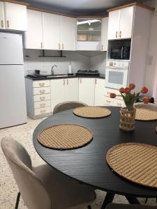 提比里亚LTD Hadas Garden apartment的一间带桌椅的厨房和一间带白色橱柜的厨房