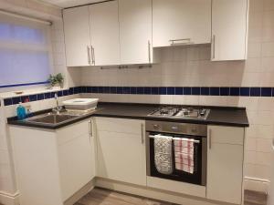 曼彻斯特Bright 4-Bed house 15 min to Manchester Centre的厨房配有白色橱柜、炉灶和水槽。