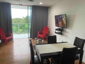 科隆Bala Beach Paradise 1-bedroom Fully Equipped apt.的客厅配有红色椅子、桌子和电视