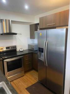 科隆Bala Beach Paradise 1-bedroom Fully Equipped apt.的厨房配有不锈钢冰箱和炉灶。