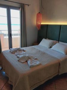 罗达Ninos On The Beach Hotel的一间卧室配有带2件浴袍的床