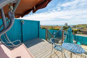 滨海比格伯里Fairwinds,Bigbury on sea ,Three-bed Beach House的甲板上配有两把椅子、一张桌子和一张桌子以及椅子