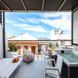 海若克利欧Porta Suites的阳台配有浴缸和桌椅。