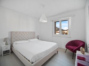 卡斯拉诺Caslano City Apartments的白色卧室,配有床和红色椅子