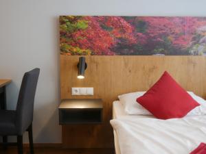 卢斯特瑙林德辛诺豪斯酒店的卧室配有红色枕头,位于床上