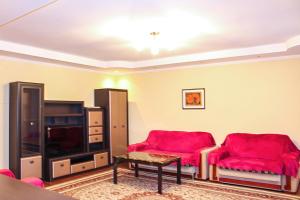 阿拉木图Tolebaeva 65的客厅配有2把红色椅子和平面电视